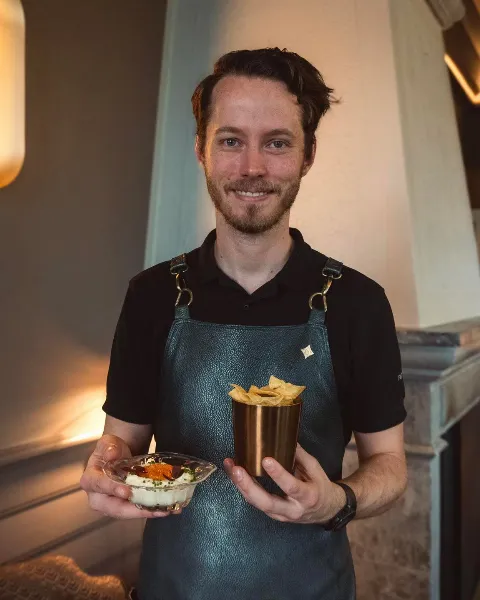 Brendan i Peisestuen med det vi vil kalle perfekt barsnacks 🤎 Potetchips og pisket Rørosrømme med sikrogn og gressløk. (Også et av Bergen…